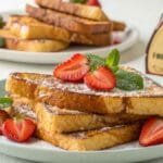 The Ultimate McCormick French Toast Hack You Need! 9 Golden French toast slices with strawberries and powdered sugar, featuring McCormick vanilla extract.