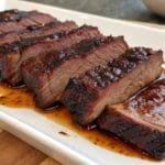 Transform Your Dinners With Boneless Beef Short Ribs Magic 9 A plate of tender, sliced barbecue beef short ribs glazed with a rich, smoky sauce, served on a white dish.