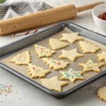 How to Make the Best Rolled Sugar Cookies for Any Occasion 10 "Freshly baked rolled sugar cookies in festive shapes with icing and sprinkles on a baking tray in a cozy kitchen setting."