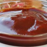 Delicious BBQ ribs glazed with thick, smoky Bar-B-Q sauce, served on a rustic wooden table with grill smoke in the background.