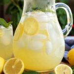 Fresh Lemonade 15 Pitcher and glasses of fresh lemonade on a sunny summer table with lemon slices and mint.